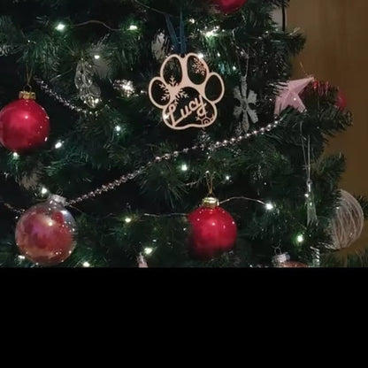 Personalised 9cm paw-shaped wooden ornament displayed among Christmas decorations
